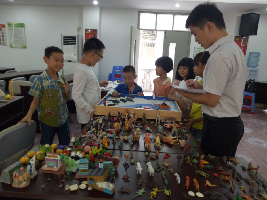 2、老师引导儿童制作沙盘.jpg
